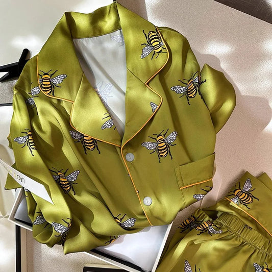 Green satin pajama set with bee embroidery on a light background
