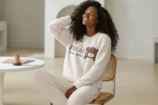 Woman wearing a fluffy white sweater with a bear design sitting on a chair.