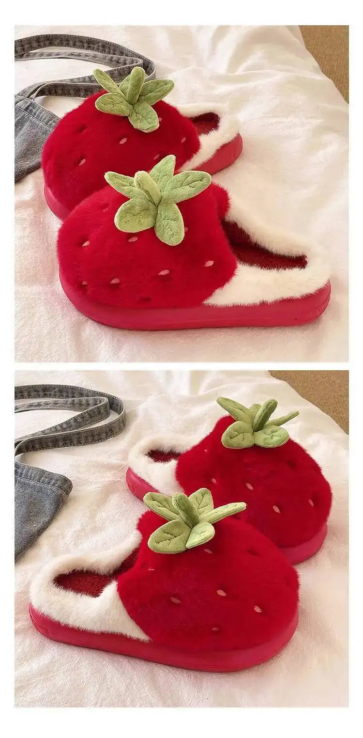 Red strawberry-shaped slippers with green leaves on a white surface.