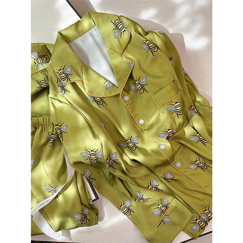Green satin pajama set with bee patterns on a light background