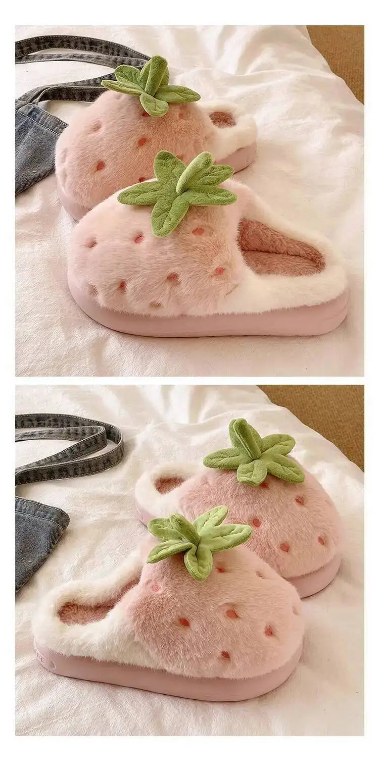 Pink strawberry-shaped slippers with green leaves on a white surface.
