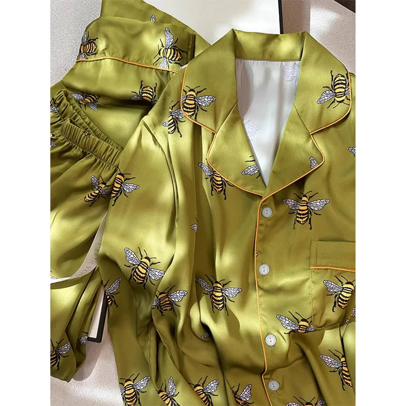 Green satin pajama set with bee patterns on a white background